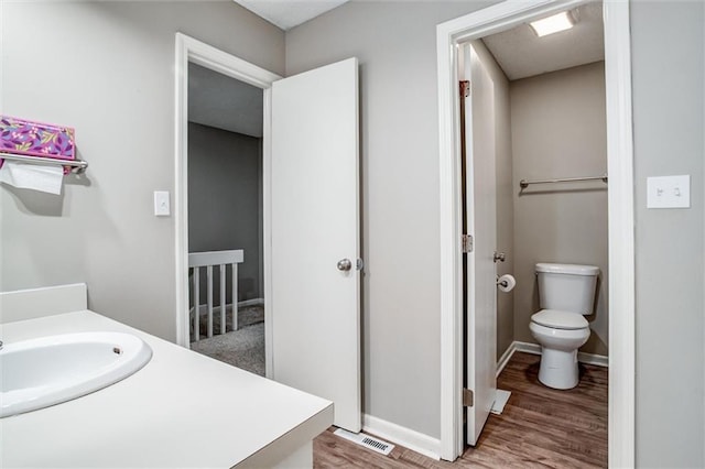 5516 66th Ter, Kansas City, MO 64151 - bathroom featuring wood finished floors, toilet, vanity, and baseboards
