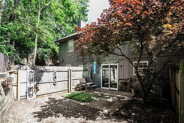 5516 66th Ter, Kansas City, MO 64151 - back of property featuring a fenced backyard, board and batten siding, a patio area, central AC unit, and a chimney