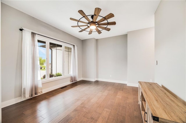 empty room with a ceiling fan, wood finished floors, and baseboards