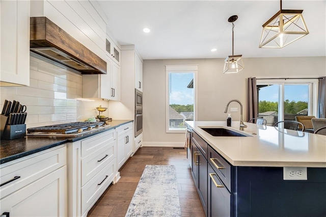 kitchen with a sink, stainless steel appliances, custom exhaust hood, dark wood-type flooring, and backsplash