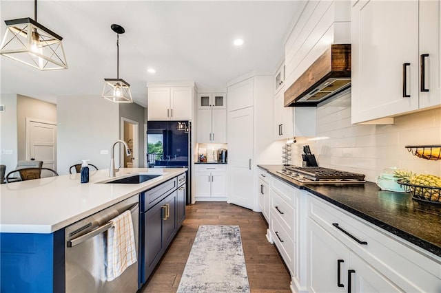 kitchen with stainless steel appliances, a sink, custom exhaust hood, white cabinets, and backsplash