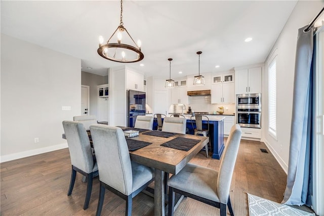 dining area featuring a chandelier, dark wood finished floors, baseboards, and recessed lighting