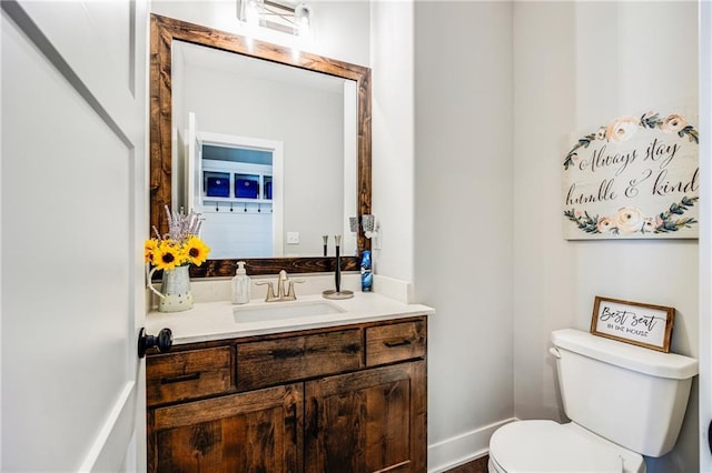 half bathroom featuring toilet, vanity, and baseboards