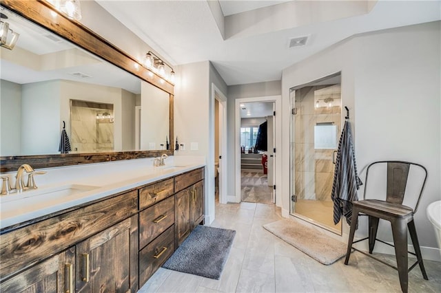 full bath with a stall shower, baseboards, and double vanity