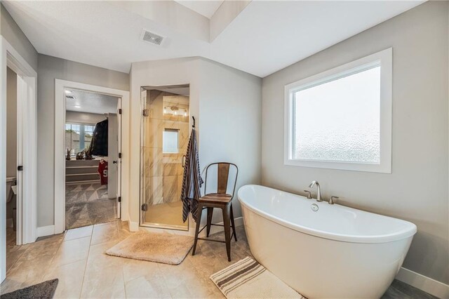 full bath featuring a stall shower, a freestanding bath, baseboards, and tile patterned floors