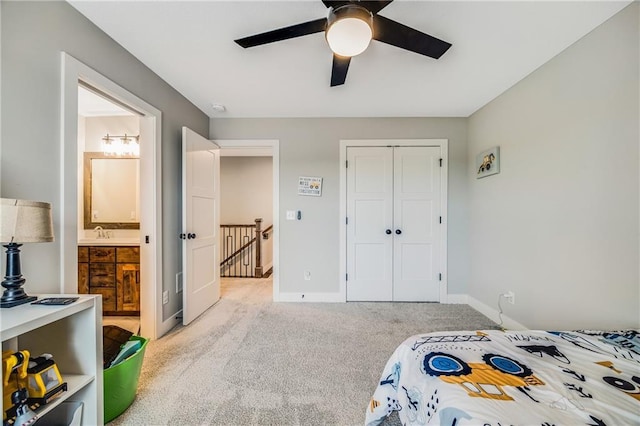 bedroom with light carpet, a closet, baseboards, and ensuite bath