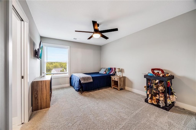 bedroom featuring light colored carpet, baseboards, and a ceiling fan