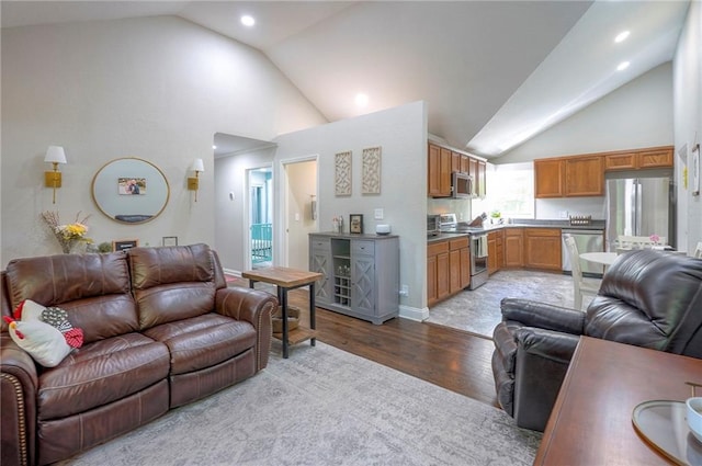 living area with light wood-style flooring, recessed lighting, and high vaulted ceiling