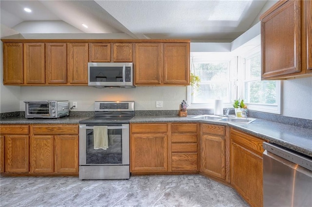 kitchen with appliances with stainless steel finishes, a sink, brown cabinetry, and recessed lighting