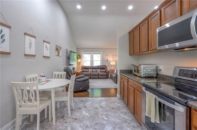 kitchen featuring appliances with stainless steel finishes, brown cabinets, lofted ceiling, open floor plan, and recessed lighting