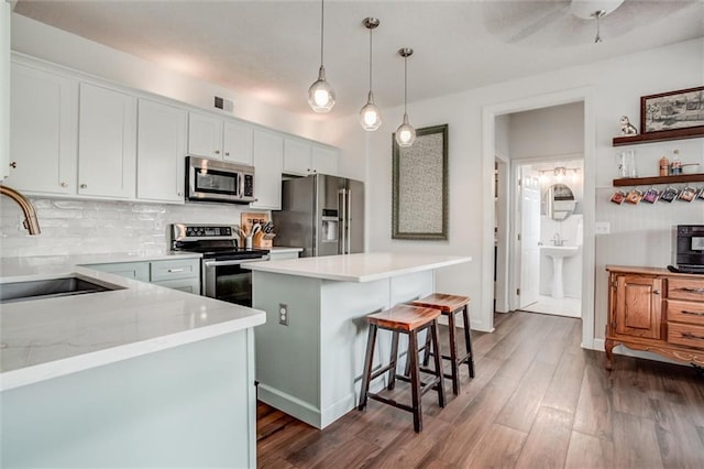 1849 W Cedar St, Olathe, KS 66061 - kitchen featuring appliances with stainless steel finishes, a kitchen island, dark wood finished floors, tasteful backsplash, and a kitchen bar