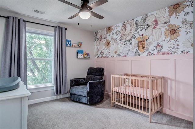 1849 W Cedar St, Olathe, KS 66061 - carpeted bedroom with a crib, a ceiling fan, a wainscoted wall, wallpapered walls, and a textured ceiling