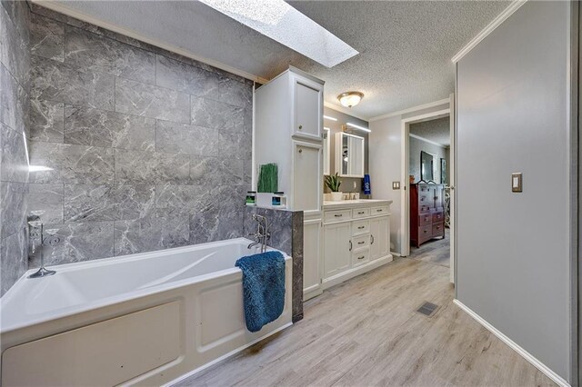 33 Lakeview Ln, Linn Valley, KS 66040 - full bathroom featuring a skylight, vanity, wood finished floors, a garden tub, and a textured ceiling