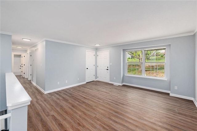unfurnished living room with ornamental molding, baseboards, and wood finished floors