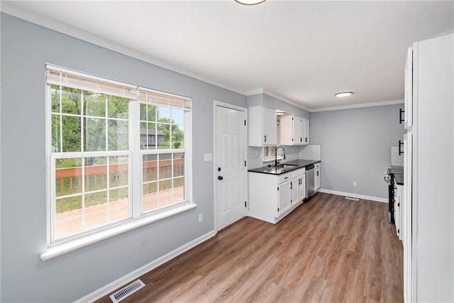 kitchen with a sink, baseboards, white cabinets, wood finished floors, and ornamental molding