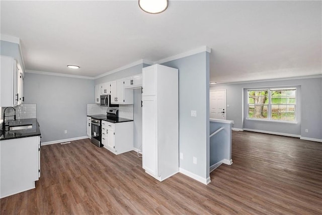 kitchen featuring appliances with stainless steel finishes, a sink, tasteful backsplash, white cabinets, and dark wood-type flooring
