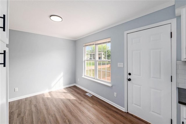 foyer featuring wood finished floors, baseboards, and ornamental molding