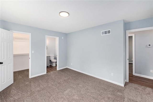unfurnished bedroom with carpet flooring, a spacious closet, and baseboards