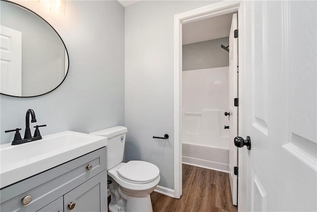 bathroom with wood finished floors, vanity, toilet, and baseboards