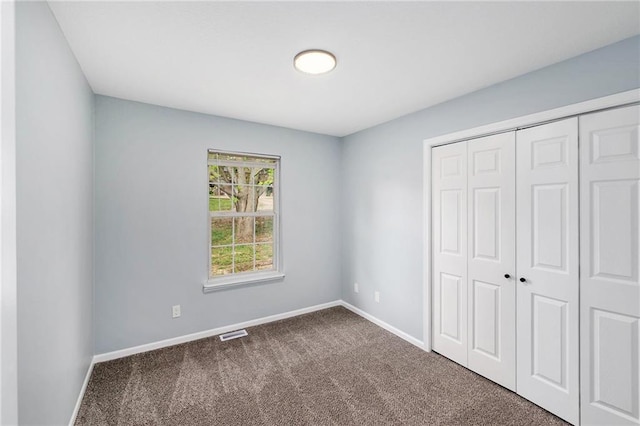 unfurnished bedroom with dark colored carpet, baseboards, and a closet
