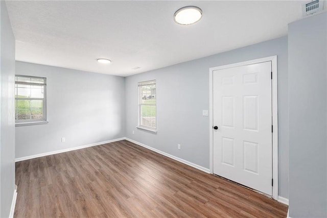 empty room featuring plenty of natural light, wood finished floors, and baseboards