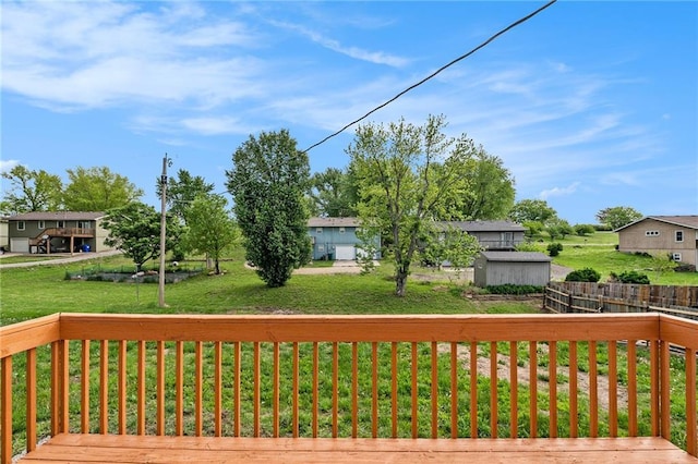 wooden deck featuring a storage unit, an outdoor structure, and a lawn