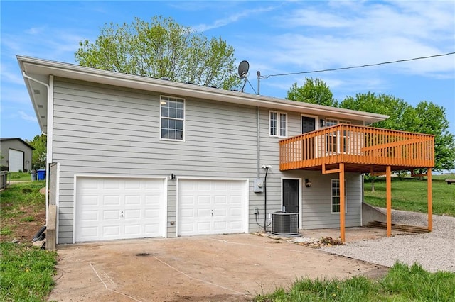back of property with a wooden deck, an attached garage, concrete driveway, and central AC unit