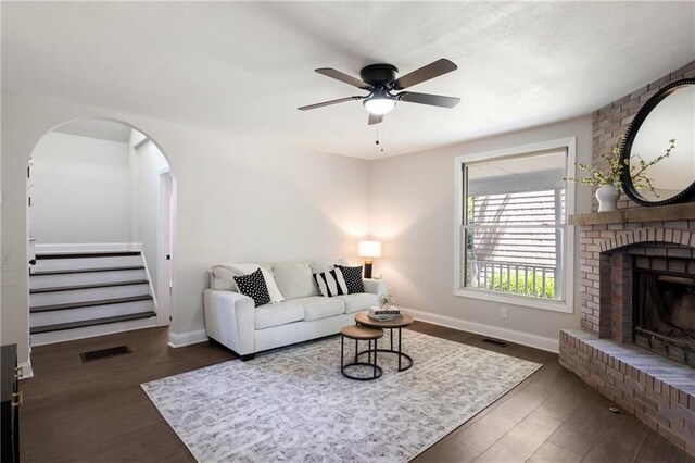 506 W 86th St, Kansas City, MO 64114 - living room featuring a ceiling fan, a brick fireplace, dark wood-style flooring, baseboards, and stairway