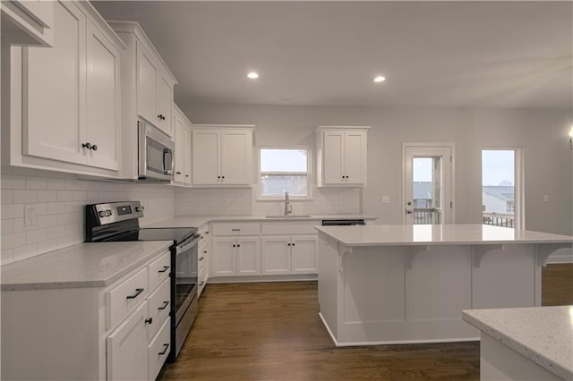6106 NE 118th St, Kansas City, MO 64156 - kitchen featuring stainless steel appliances, a sink, a kitchen breakfast bar, decorative backsplash, and white cabinets