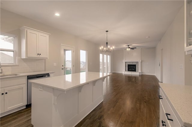 6106 NE 118th St, Kansas City, MO 64156 - kitchen featuring dishwasher, a fireplace with raised hearth, a sink, white cabinets, and tasteful backsplash