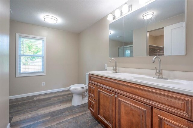 507 W 26th St, Higginsville, MO 64037 - full bathroom featuring wood finished floors, toilet, double vanity, and baseboards