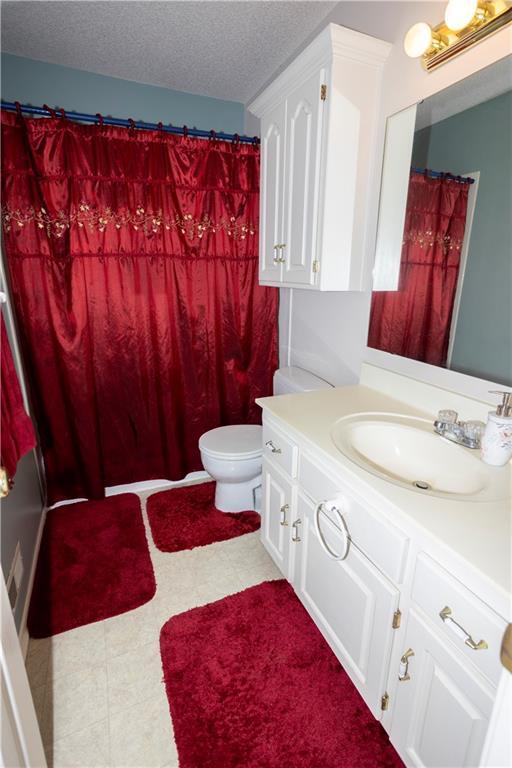 16366 S Hunter St, Olathe, KS 66062 - full bathroom with vanity, toilet, a textured ceiling, and a shower with curtain