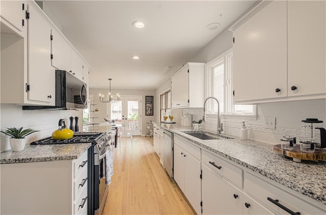 4547 Wyoming St, Kansas City, MO 64111 - kitchen with stainless steel appliances, a sink, tasteful backsplash, light wood-style flooring, and white cabinetry