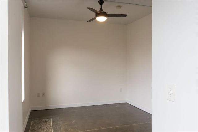 empty room featuring concrete floors, ceiling fan, and baseboards