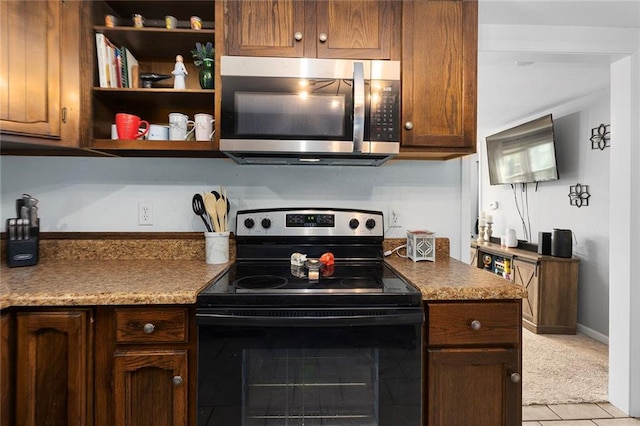 kitchen featuring stainless steel microwave, electric range, and light tile patterned flooring