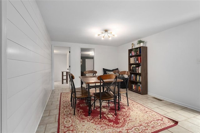 dining area with light tile patterned floors, a chandelier, and baseboards