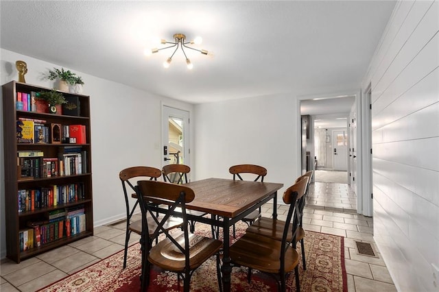 dining area with light tile patterned floors and a chandelier