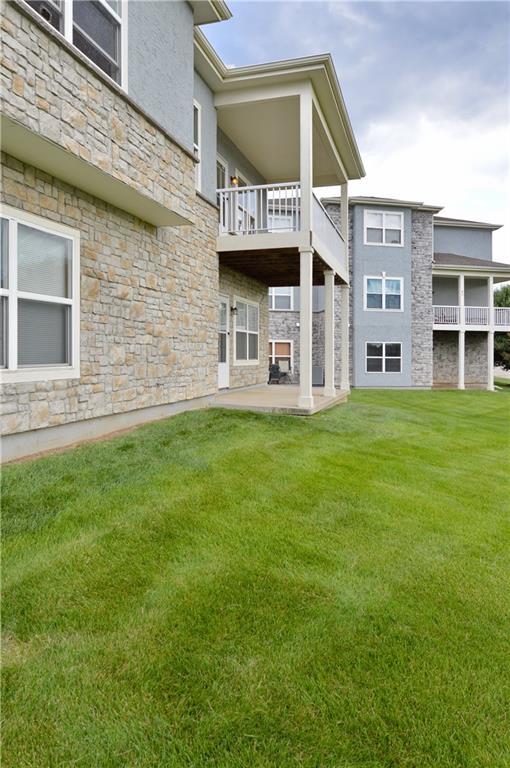 21962 W 116th Ter, Olathe, KS 66061 - back of property with stone siding, a balcony, a yard, and a patio