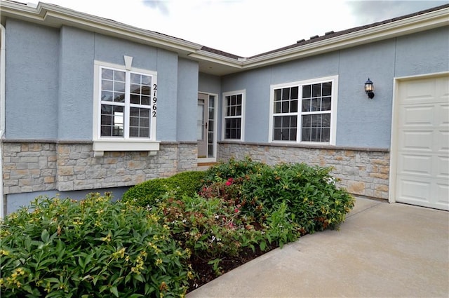 21962 W 116th Ter, Olathe, KS 66061 - entrance to property with stone siding, stucco siding, driveway, and an attached garage