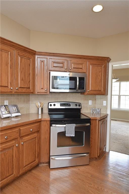 21962 W 116th Ter, Olathe, KS 66061 - kitchen with stainless steel appliances, brown cabinetry, and tasteful backsplash
