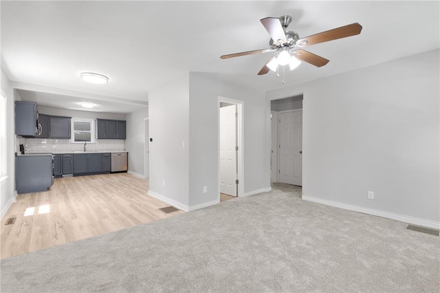 522 E Fair Ave, Independence, MO 64055 - unfurnished living room with light carpet, ceiling fan, baseboards, and a sink
