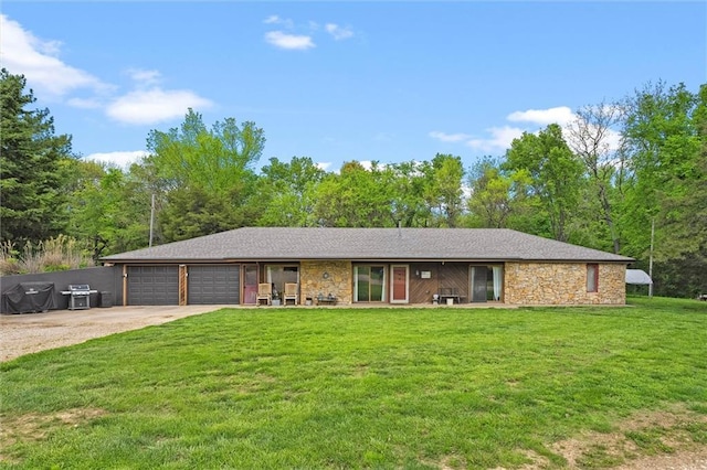 ranch-style home with driveway, a front yard, a garage, and stone siding