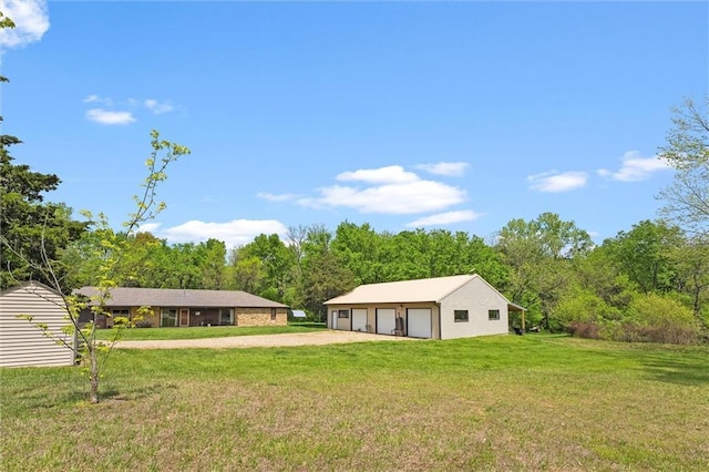 rear view of property featuring a detached garage, an outbuilding, a yard, and a forest view