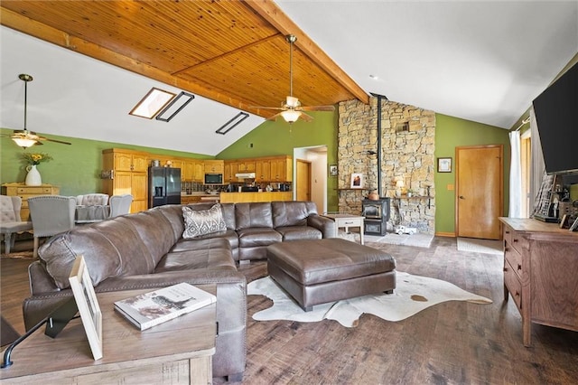 living room with a ceiling fan, a wood stove, and wood finished floors