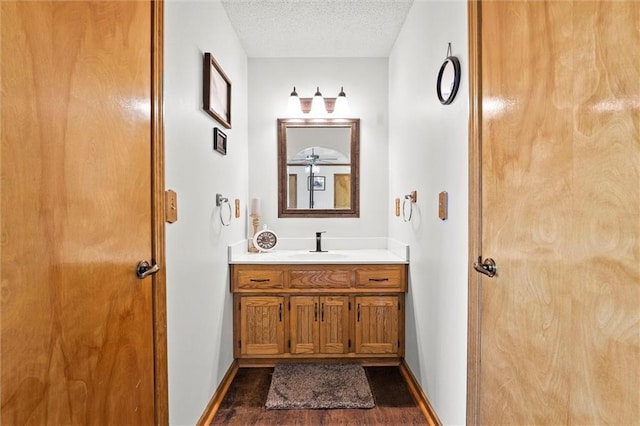 bathroom featuring a textured ceiling, wood finished floors, vanity, and baseboards