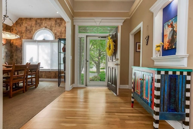 entrance foyer with baseboards, wood finished floors, healthy amount of natural light, crown molding, and vaulted ceiling