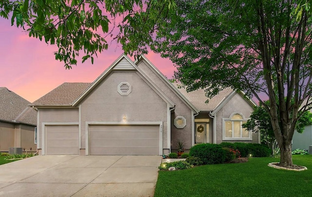 view of front facade featuring an attached garage, concrete driveway, a lawn, and stucco siding