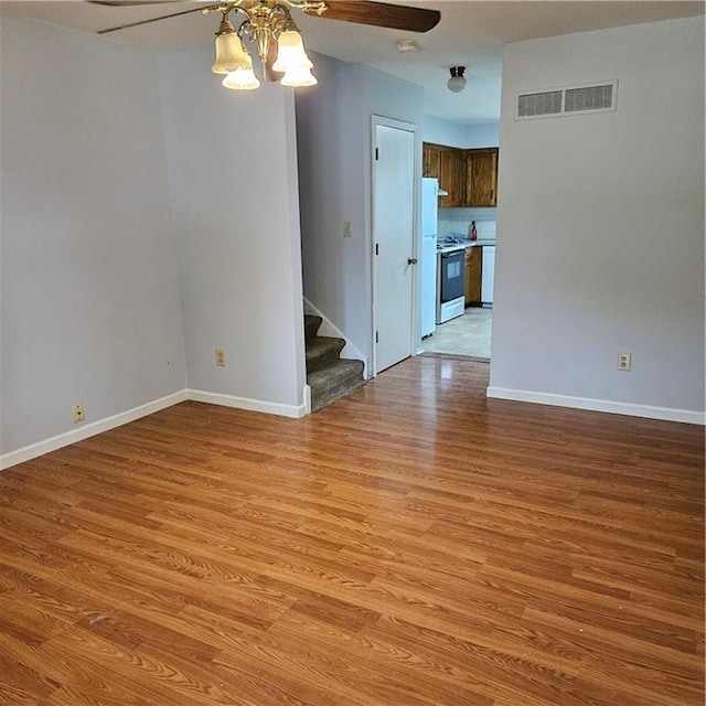 8413-8415 E 170th St, Belton, MO 64012 - empty room with a chandelier, light wood-style flooring, stairway, baseboards, and a ceiling fan