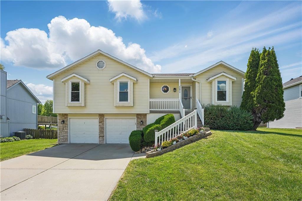 10912 N Farley Ave, Kansas City, MO 64157 - view of front of home with a garage, driveway, a front yard, and stairs