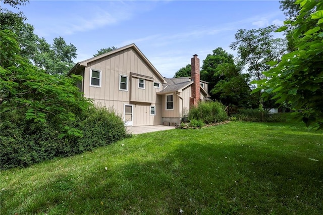 16280 Nall Ave, Stilwell, KS 66085 - back of house featuring board and batten siding, a lawn, a chimney, and a patio
